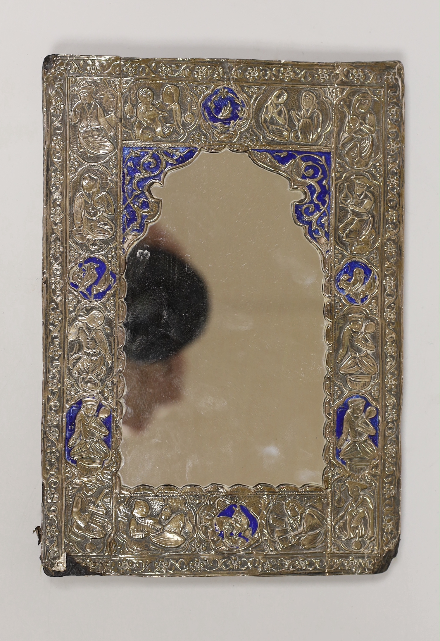 A Persian white metal overlaid mirror embossed with figures and flowers together with a faux tortoiseshell style frame, the largest 21cm high